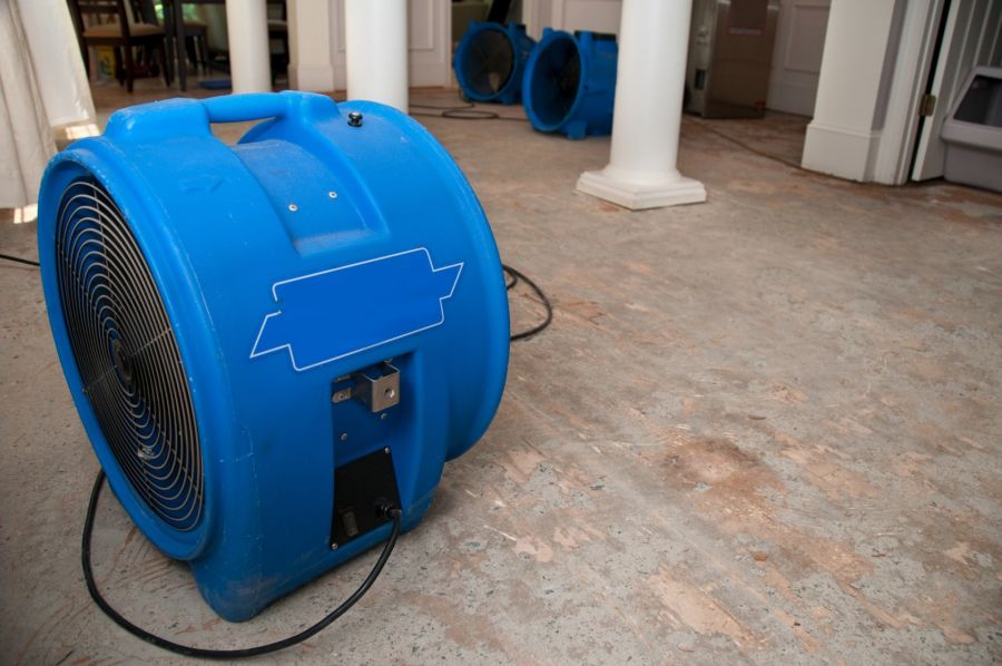 Blue industrial air movers drying a water-damaged floor in a room